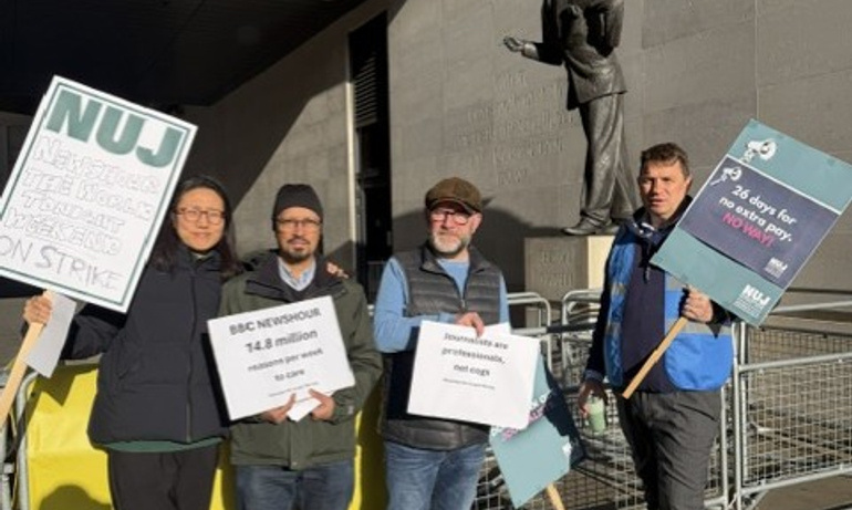Four NUJ members hold signs on the picket line outside Broadcasting House