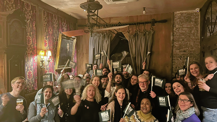 People smiling and holding green NUJ flags in a celebratory fashion.