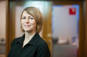 Jo wears a black blouse and has a brown bob. She smiles for a photo.