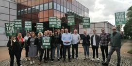 Journalists on picket hold green placards with white text 'Stop the cuts'