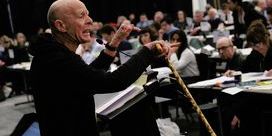 Eamonn McCann wearing a black sweatshirt and holding a walking stick speaks at DM 2025.