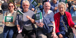 Members of the Sunderland, Shields and Hartlepool branch pose outside the river Wear with green
NUJ flags with cloudy blue skies in the background.