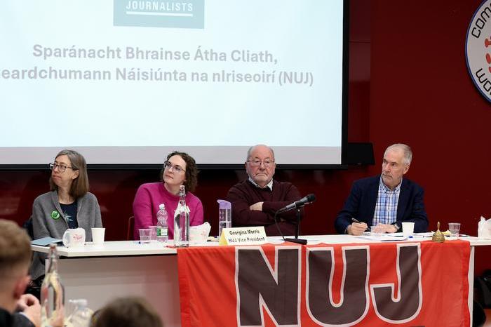 Laura Davison, Georgina Morris, Martin Fitzpatrick and Conor Kavanagh sit from left to right on a table with a red NUJ banner draped over the front.