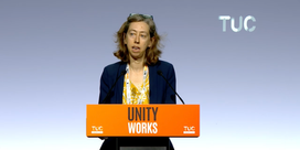 Laura Davison speaking behind an orange lectern with the slogan 'Unity Works' at the 2026 TUC Congress.