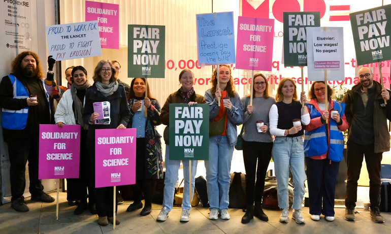 A group of people holding placards that say 'Fair Pay Now' and 'Solidarity for Science' with a glass building.