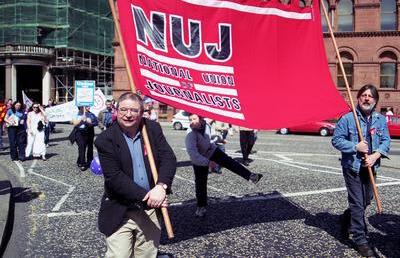 Martin O'Hagan holds red NUJ flag with another man.