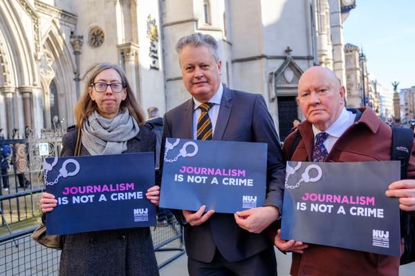 Vincent Kearney, Laura Davison and Séamus Dooley holding 'Journalism Is Not A Crime' signs outside the Royal Courts of Justice