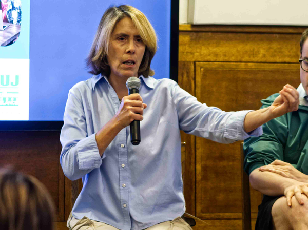 Grace Livingstone holding a microphone and gesturing while wearing a pale blue shirt.