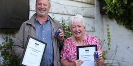 Gilbert Johnston wearing a grey jacket and Caroline Sword wearing a pink top hold their NUJ gold badges and certificates.