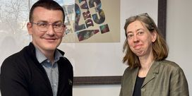 Sergiy Tomilenko, wearing a black cardigan, shakes hands with Laura Davison, wearing a grey blazer.