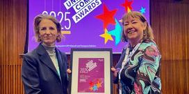 Kate Bell (left) and Christine Buckley (right) hold a plaque in front of a purple 'Trade Union Comms Awards' banner.