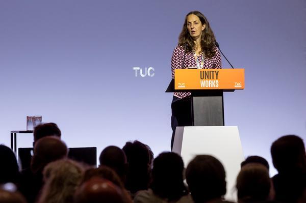 Natasha Hirst speaking behind an orange lectern with 'Unity Works' written on it at TUC Congress 2026.