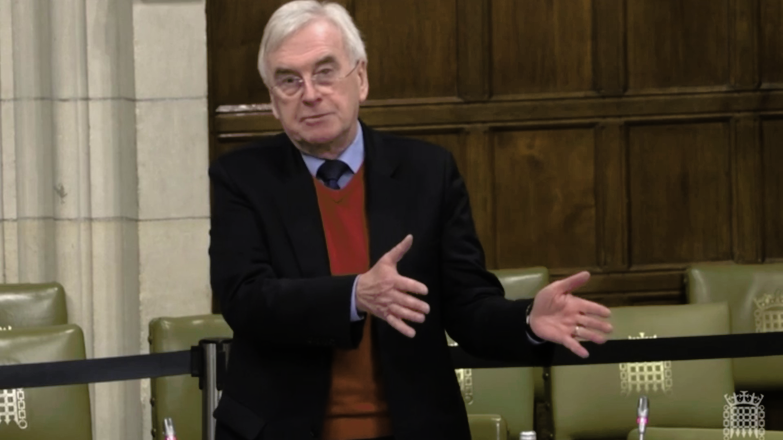 John McDonnell wearing a blazer blazer, a brown jumper and a tie.