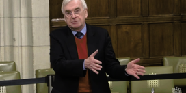 John McDonnell wearing a blazer blazer, a brown jumper and a tie.