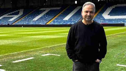 Barnie Choudhury standing in the Oldham FC stadium.