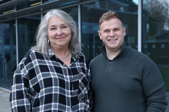 Carolyn Farrar, wearing a checked shirt, stands next to Stephen Corrigan, wearing a dark grey jumper.