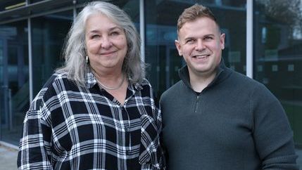 Carolyn Farrar, wearing a checked shirt, stands next to Stephen Corrigan, wearing a dark grey jumper.