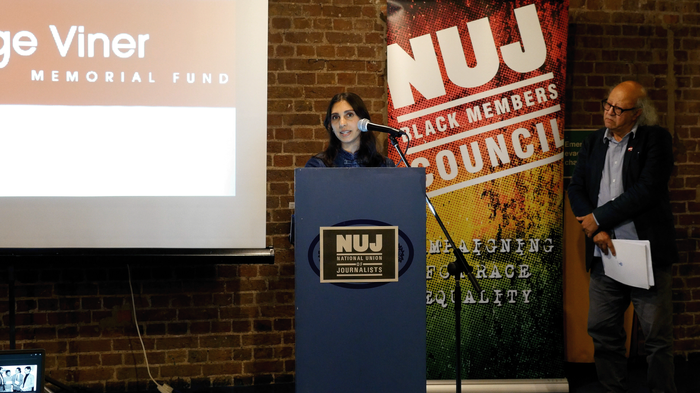 Hana Williams stands behind a microphone and blue podium with a green NUJ logo and an NUJ Black Members' Council banner to her right.