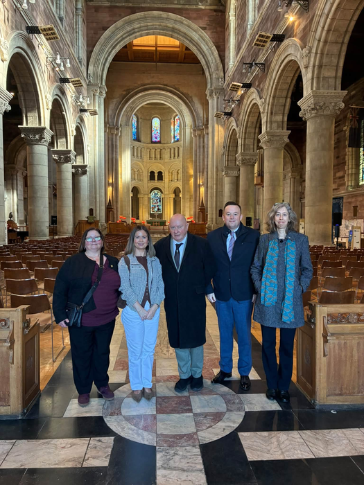 Five people standing in a line in the nave of a cathedral. 