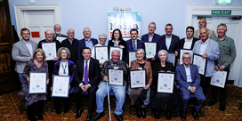 NUJ Life Members pose holding plaques in front of a light blue wall.